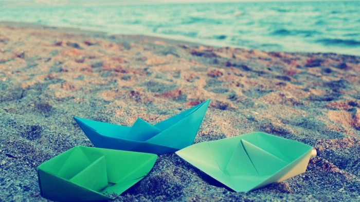 three paper boats on sand during daytime macro