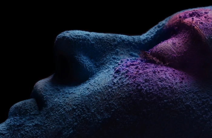 person face person's with blue and purple powder in dark room 2k
