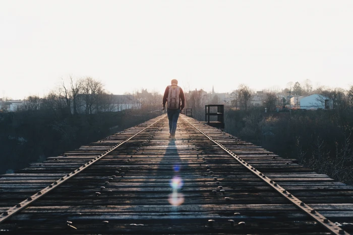 man carrying backpack while walking along wooden road men brown 2k