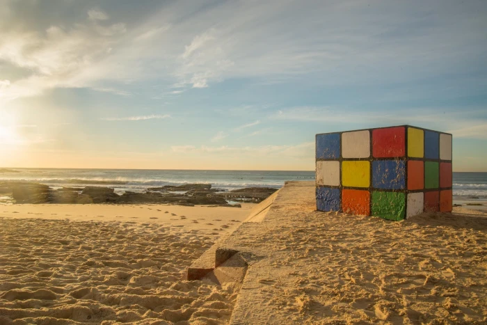 selective focus photography of Rubik's cube on beach sand 2k