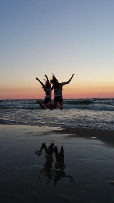 two women jumping on seashore best friends sunset beach cheer 2k