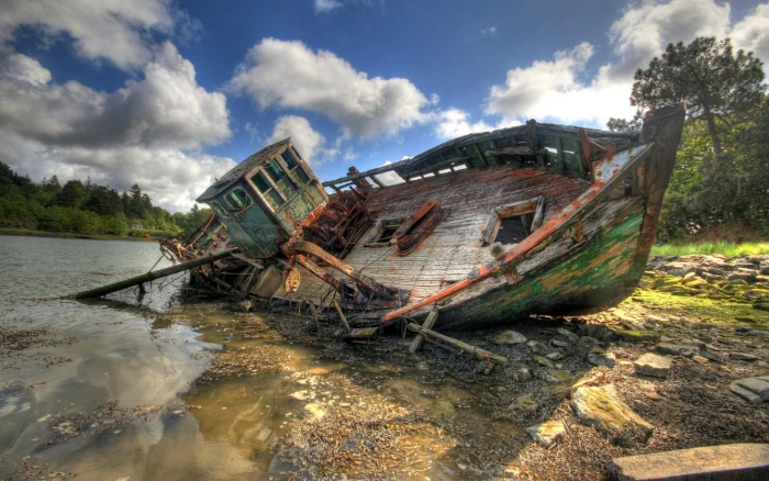 rusted green boat wrecked brown and under cloudy blue sky during daytime 2k