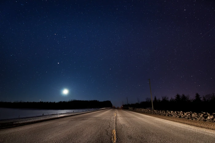 road beside the body of water during nighttime stars starry night 2k