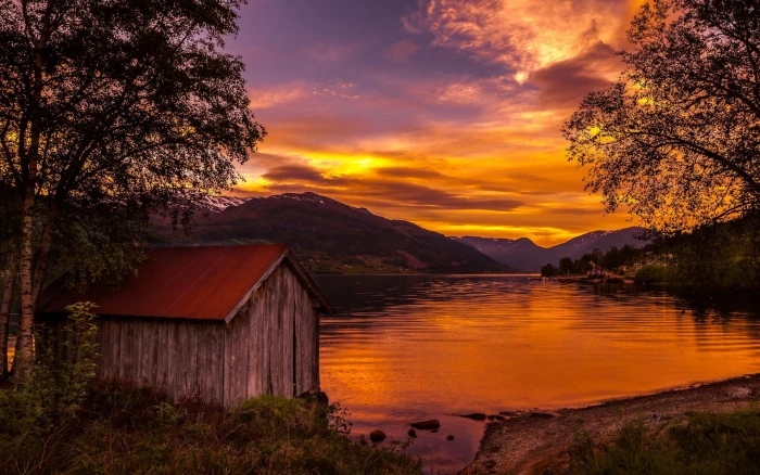 brown wooden shed near body of water and mountain at sunset nature 2k
