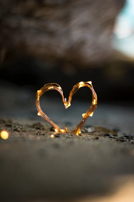close up photography of heart shaped fairy lite on brown sand 2k 4k