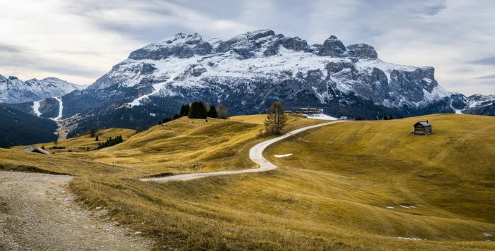 green grass field on top of mountain with brown wooden house dolomites alta badia italy 2k