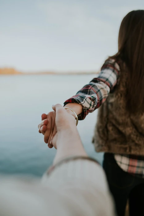 shallow focus photography of man and woman holding hands facing body water while person s hand 2k 4k