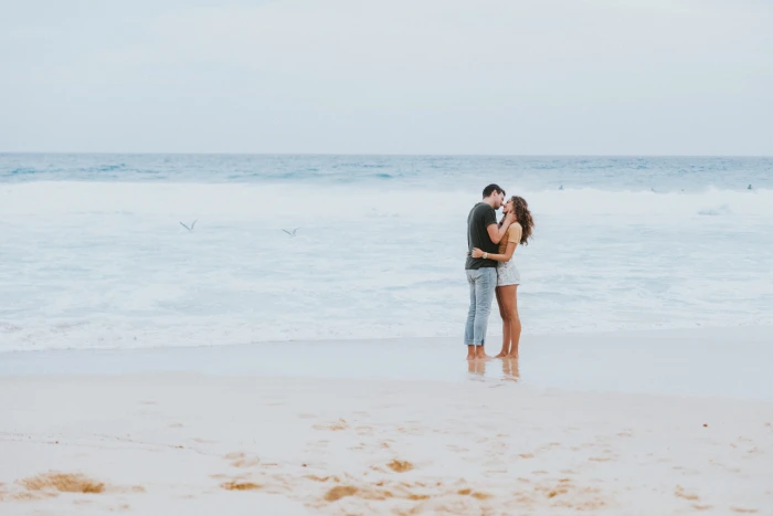 man and woman kissing each other on the seashore near beach 2k 4k 5k