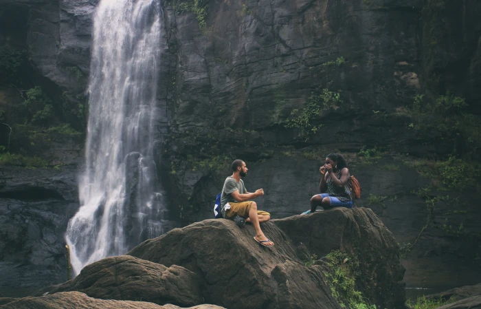 people sitting on rock near waterfalls Love Couple Woman young 2k 4k 5k