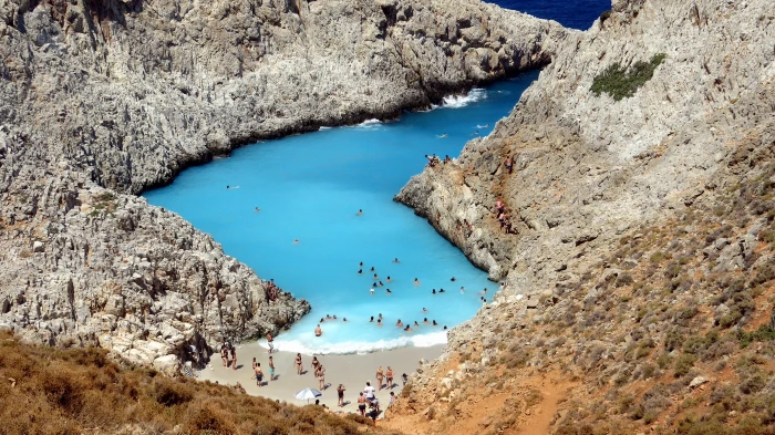 blue ocean surrounded by brown massive rock formation photography during daytime 2k 4k
