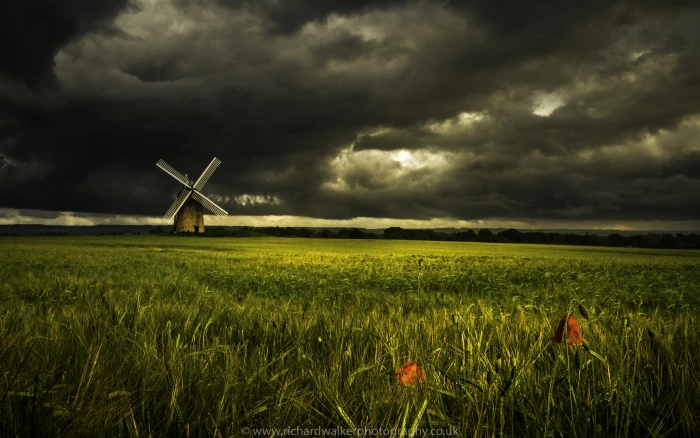 painting of grass fields near brown and gray windmill under a black sky 2k 4k 5k