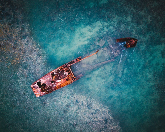 aerial view of brown ship on body water and black boat sinking in 2k 4k