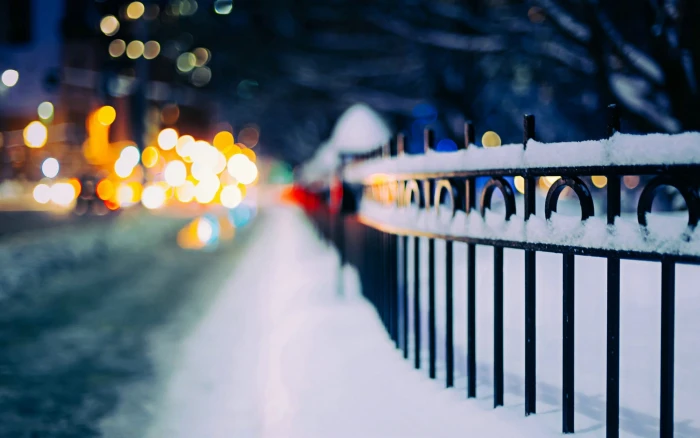 black metal fence covered with snow urban street 2k