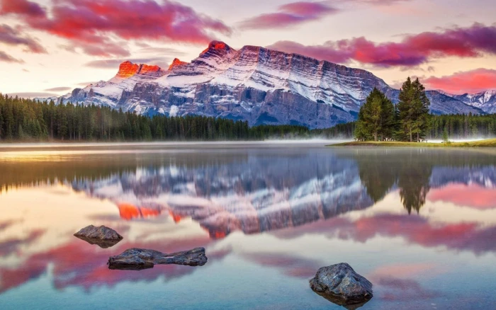 reflective photography of mountain near body water surrounded by trees 2k