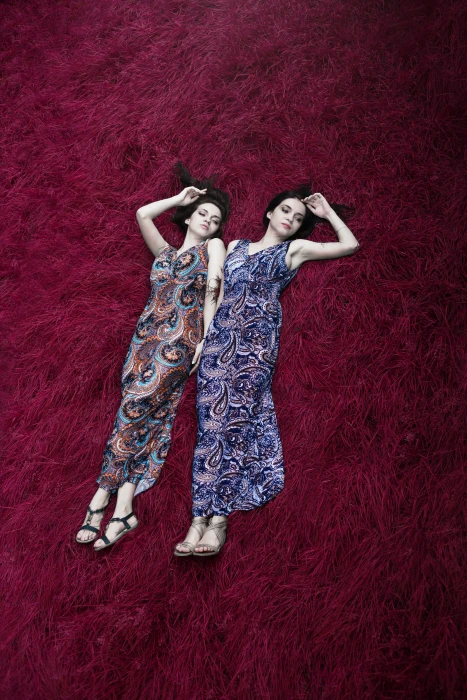 two women wearing multicolored paisley print dresses lying on red surface 2k 4k