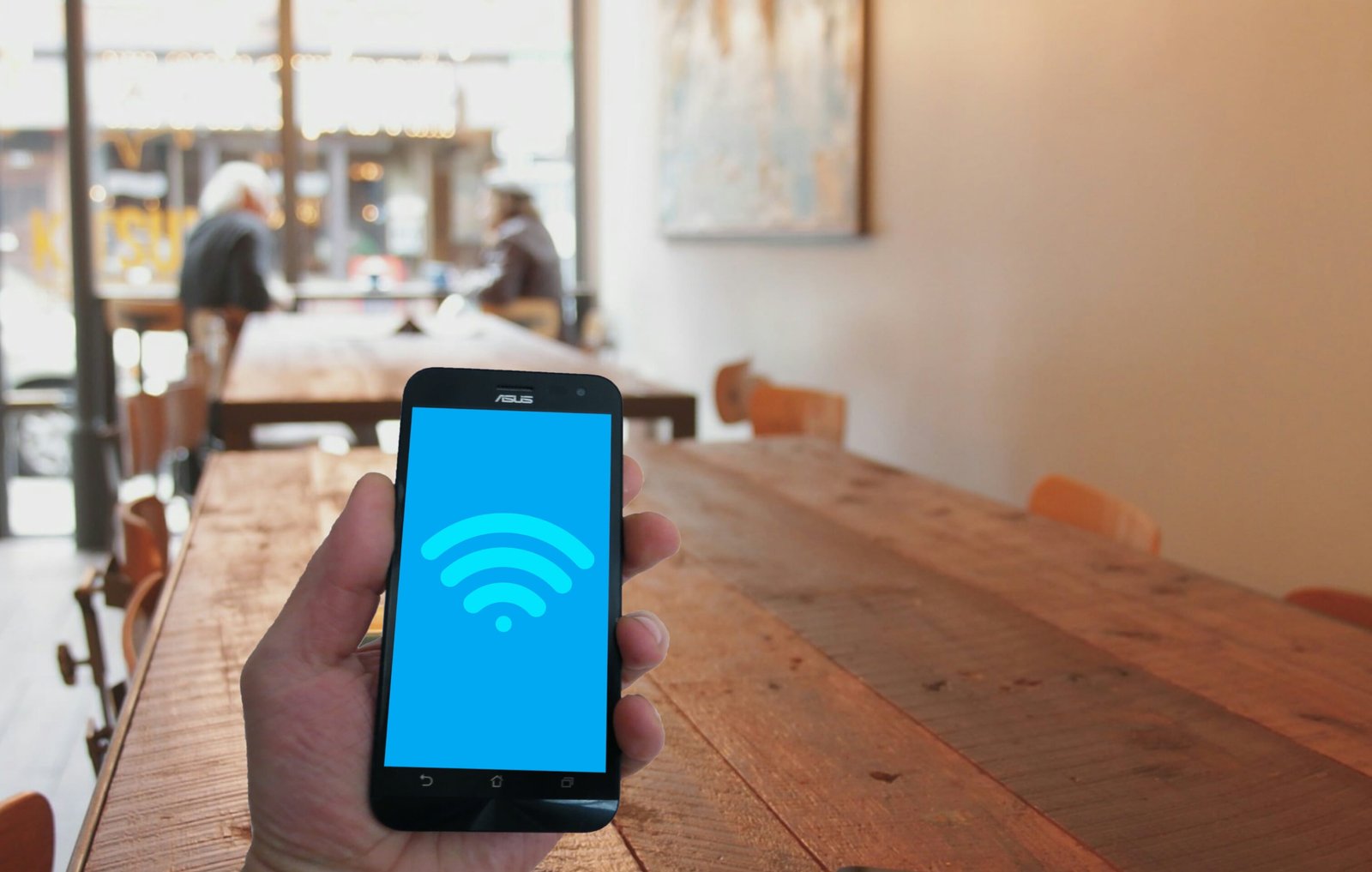 Handheld phone showing WiFi hotspot icon in coffee shop the city 2k