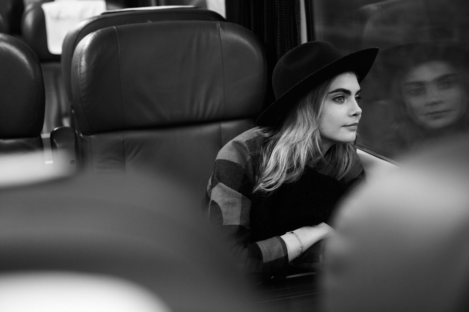 grayscale photo of woman wearing hat and sweater inside vehicle