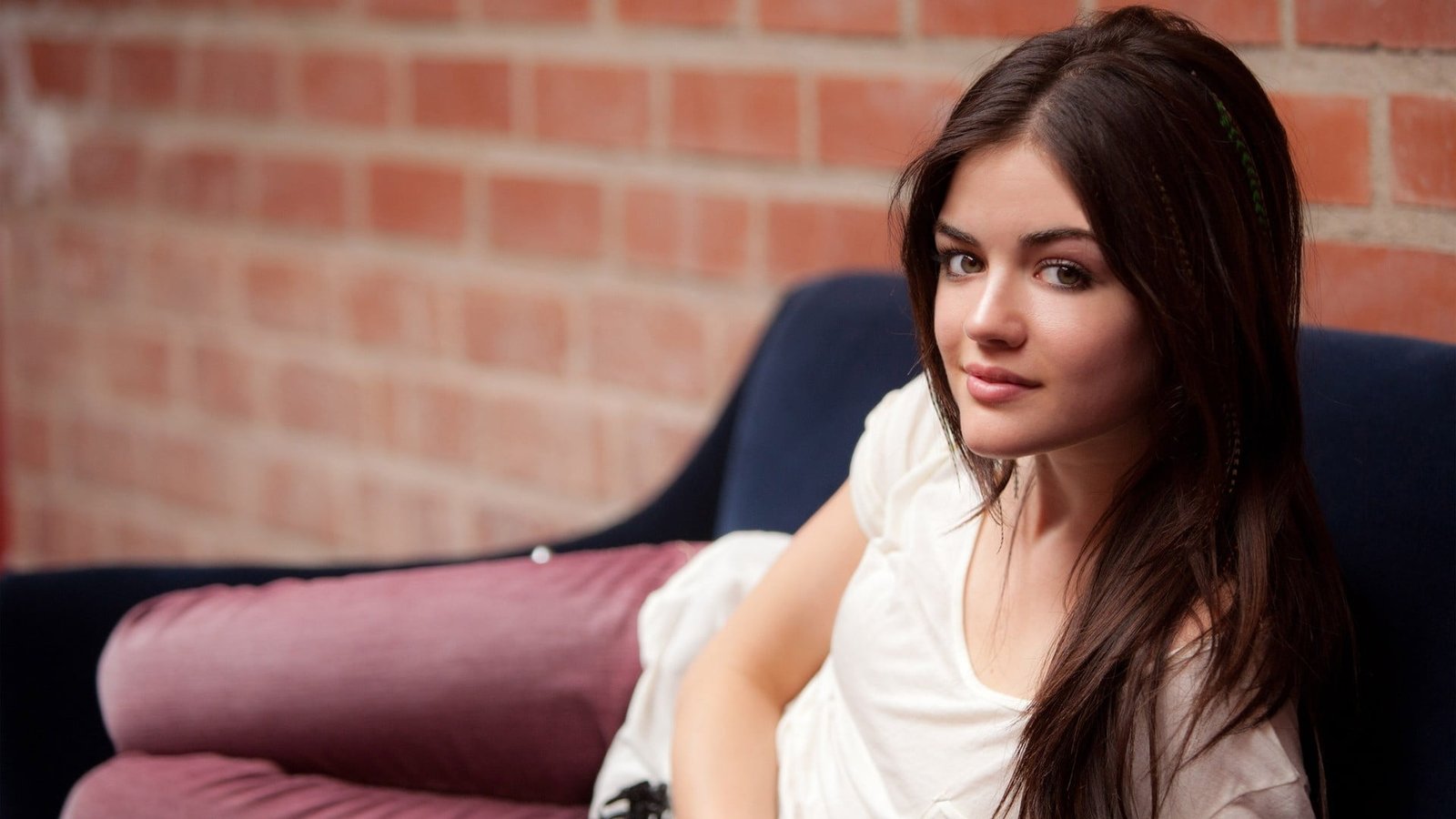 woman wearing white scoop neck cap sleeved shirt and pink skinny jeans sitting on sofa