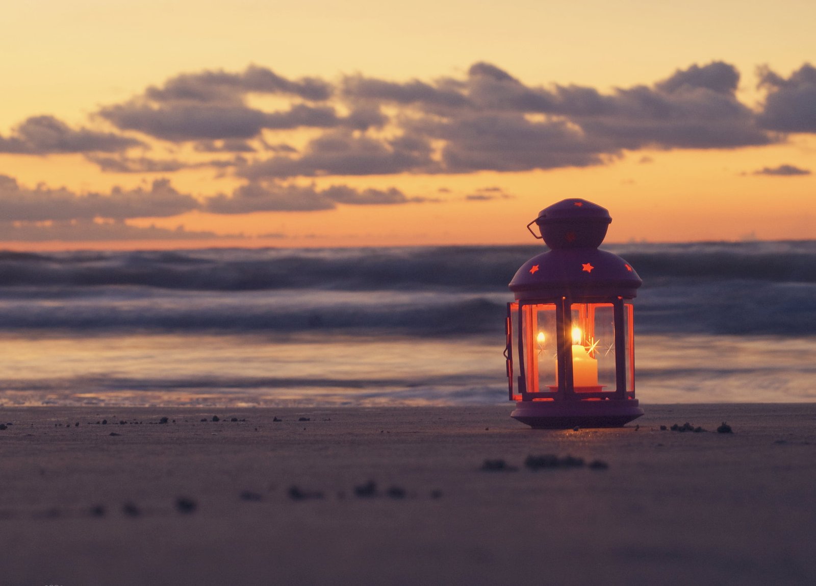white pillar candle with lantern sand sea beach the sky clouds 2k