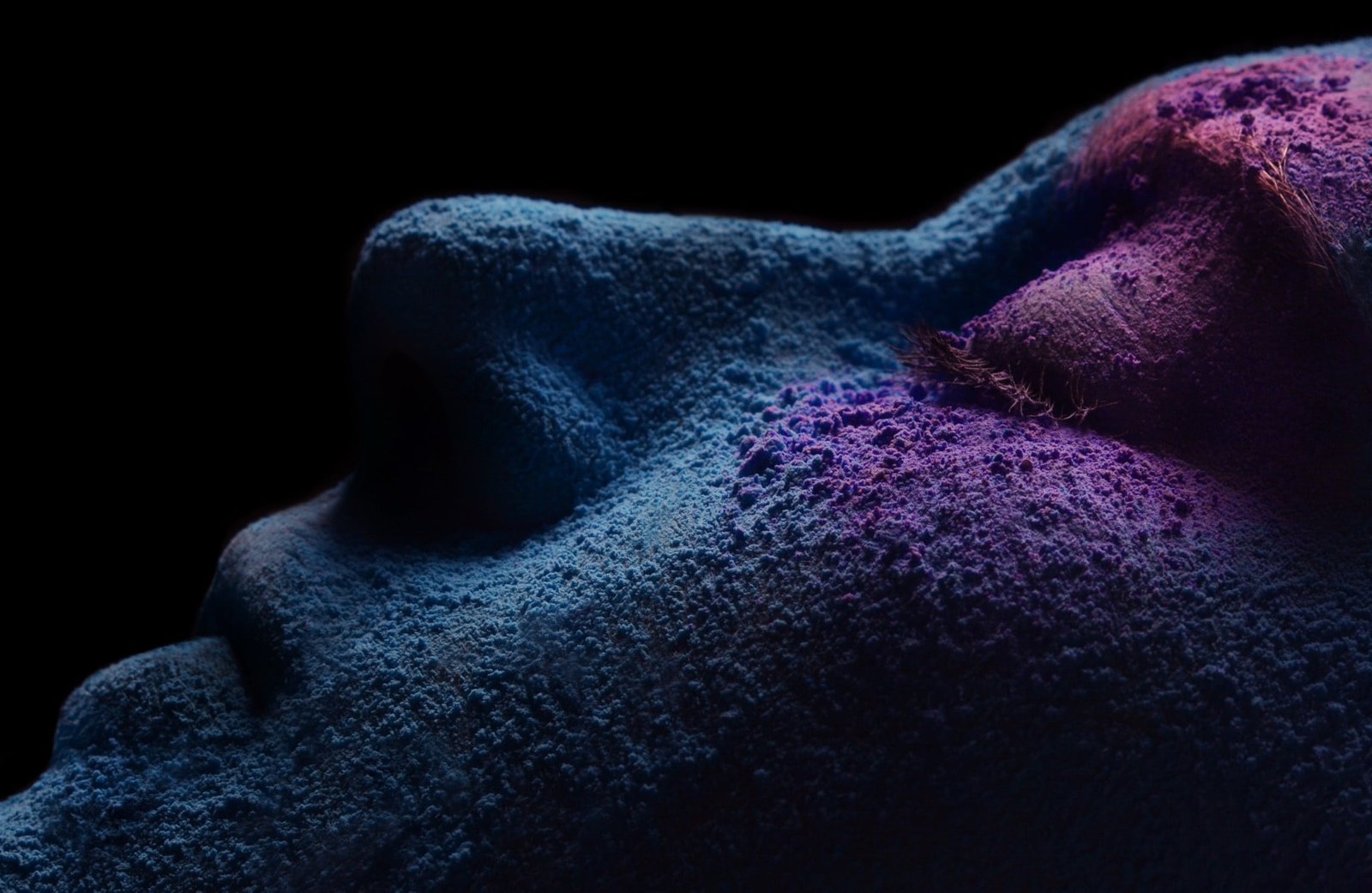 person face person's with blue and purple powder in dark room 2k