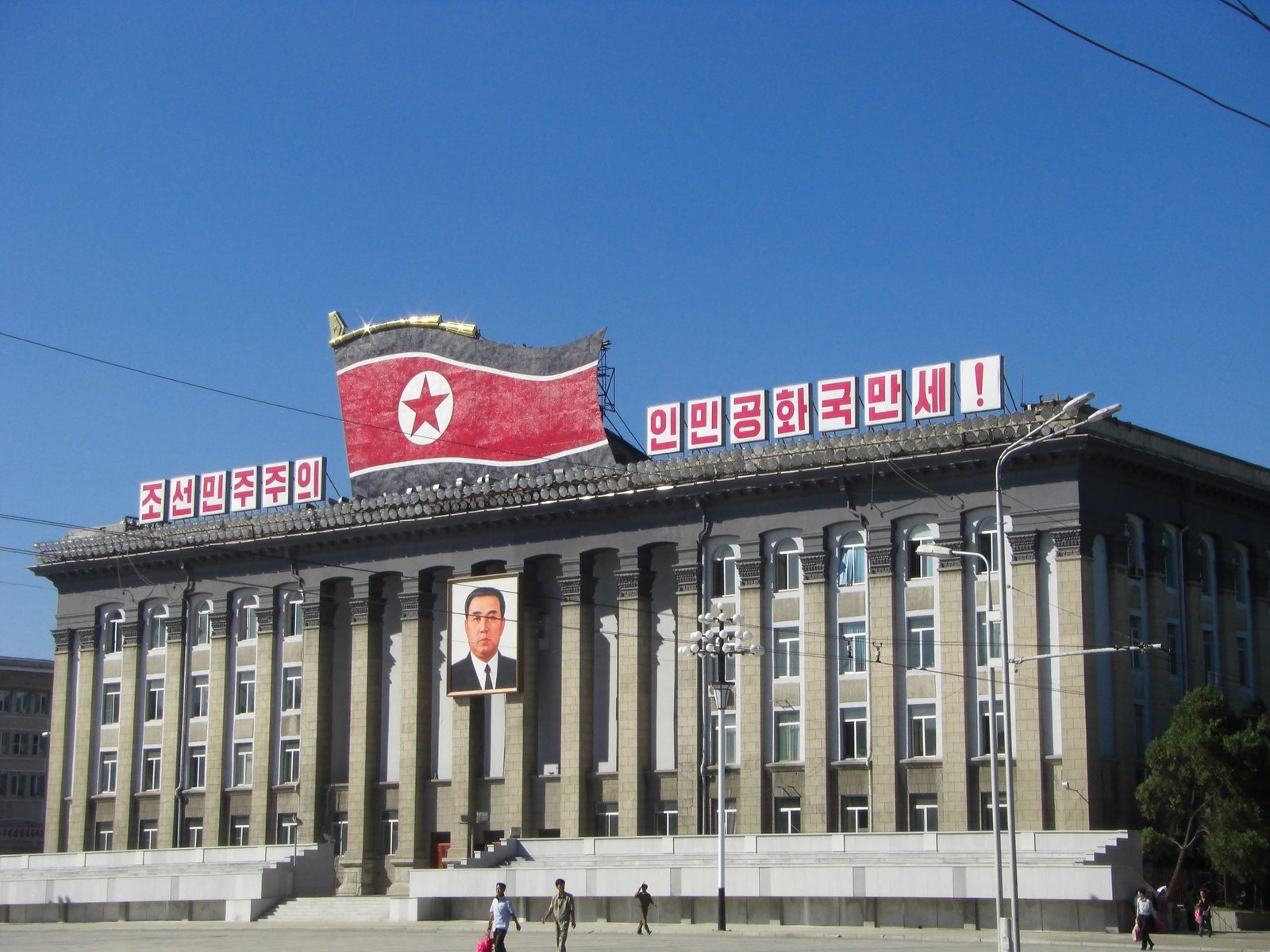 red flag on roof top north korea pyongyang building kim il sung square 2k