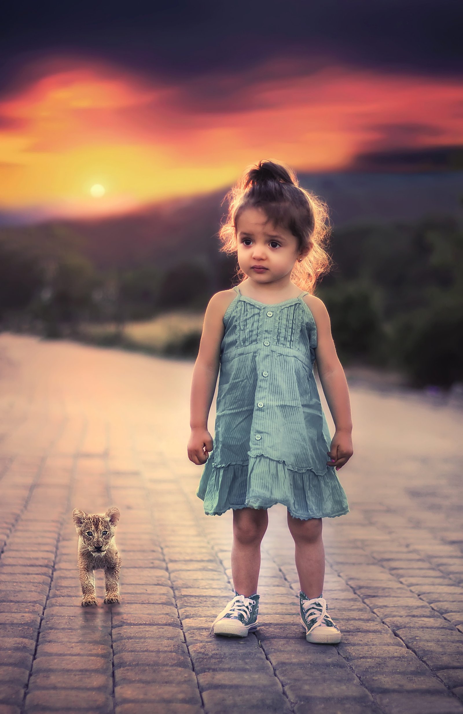 toddler girl s in green spaghetti strap dress and pair of blue white low top sneakers standing beside lon cab on grey concrete road 2k