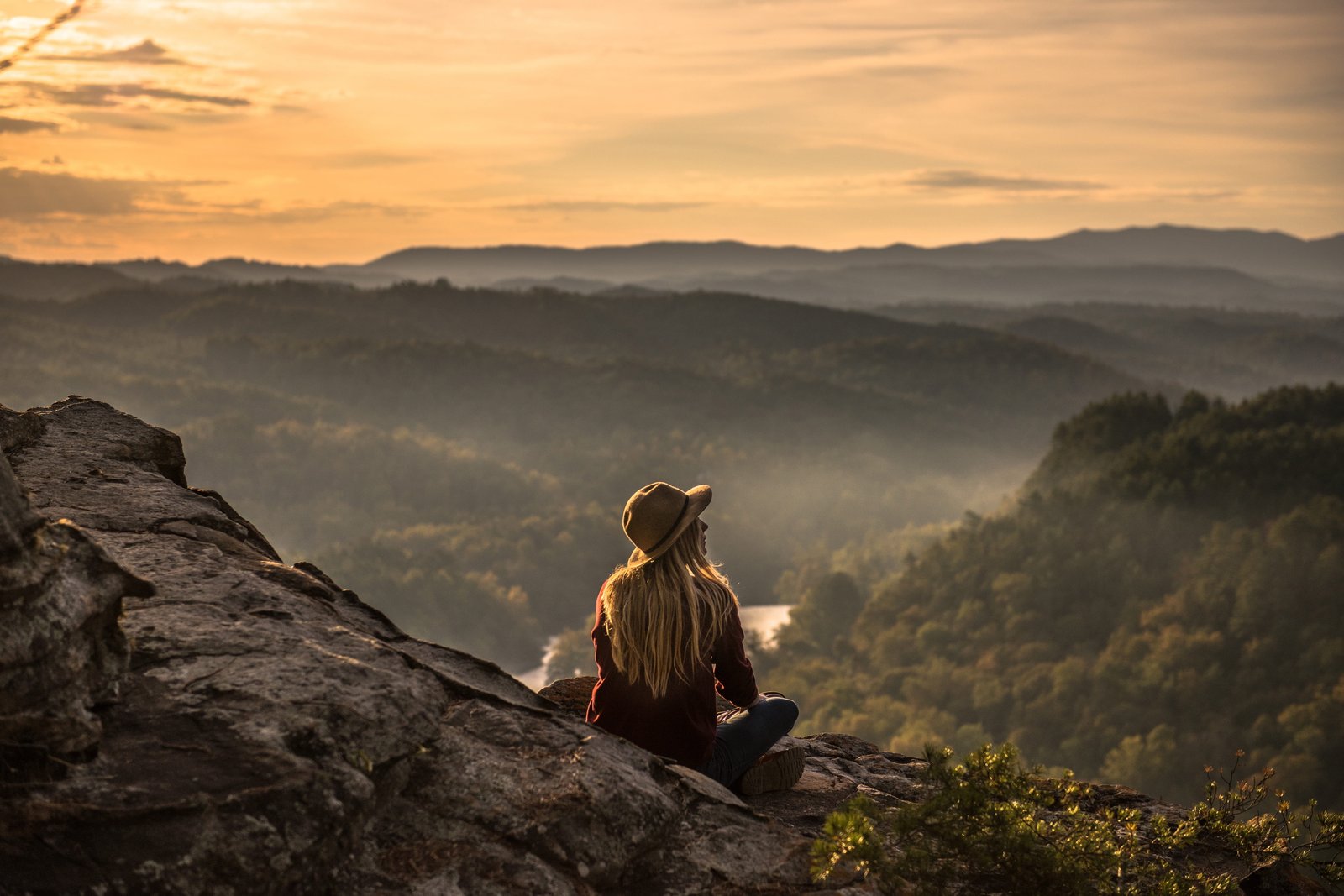 A woman wearing a hat sits on area with mountains people girl 2k 4k 5k