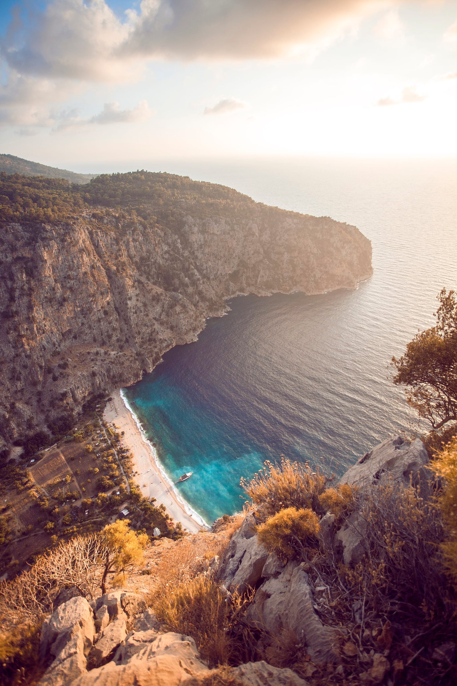 landscape photography of body water and clff white boat on the during daytime 2k