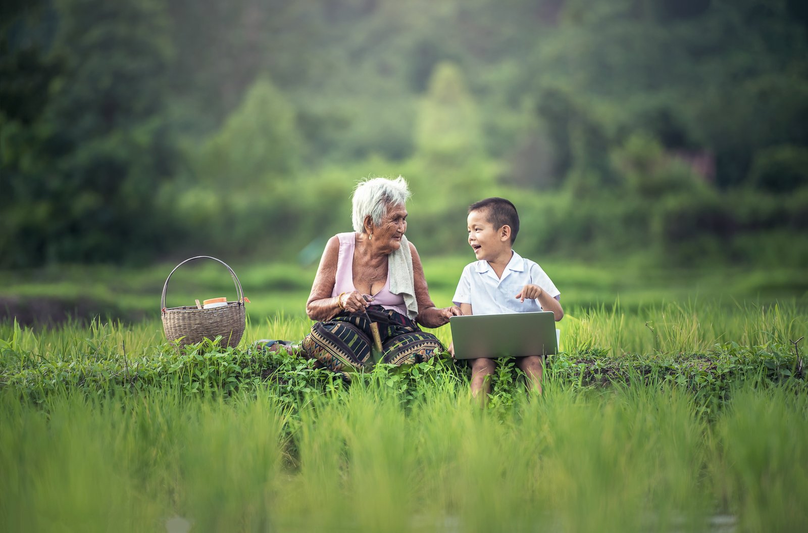 boy with laptop sitting beside white haired woman on green field 2k 4k 5k