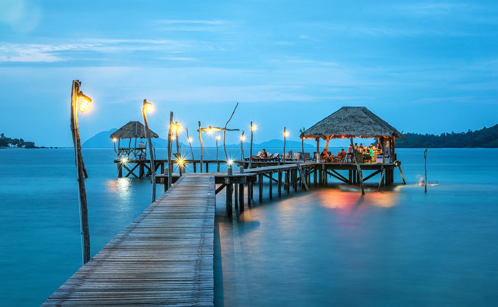 person taking photo of brown wooden dock with blue body water 2k 4k 5k