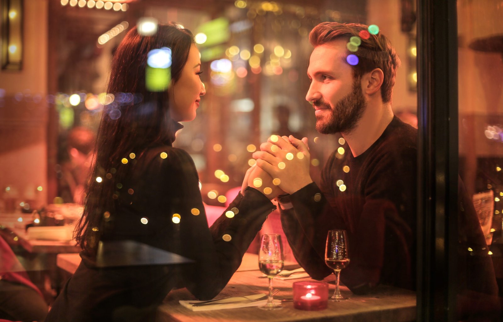 Romantic couple holding hands together over candlelight during romantic dinner 2k