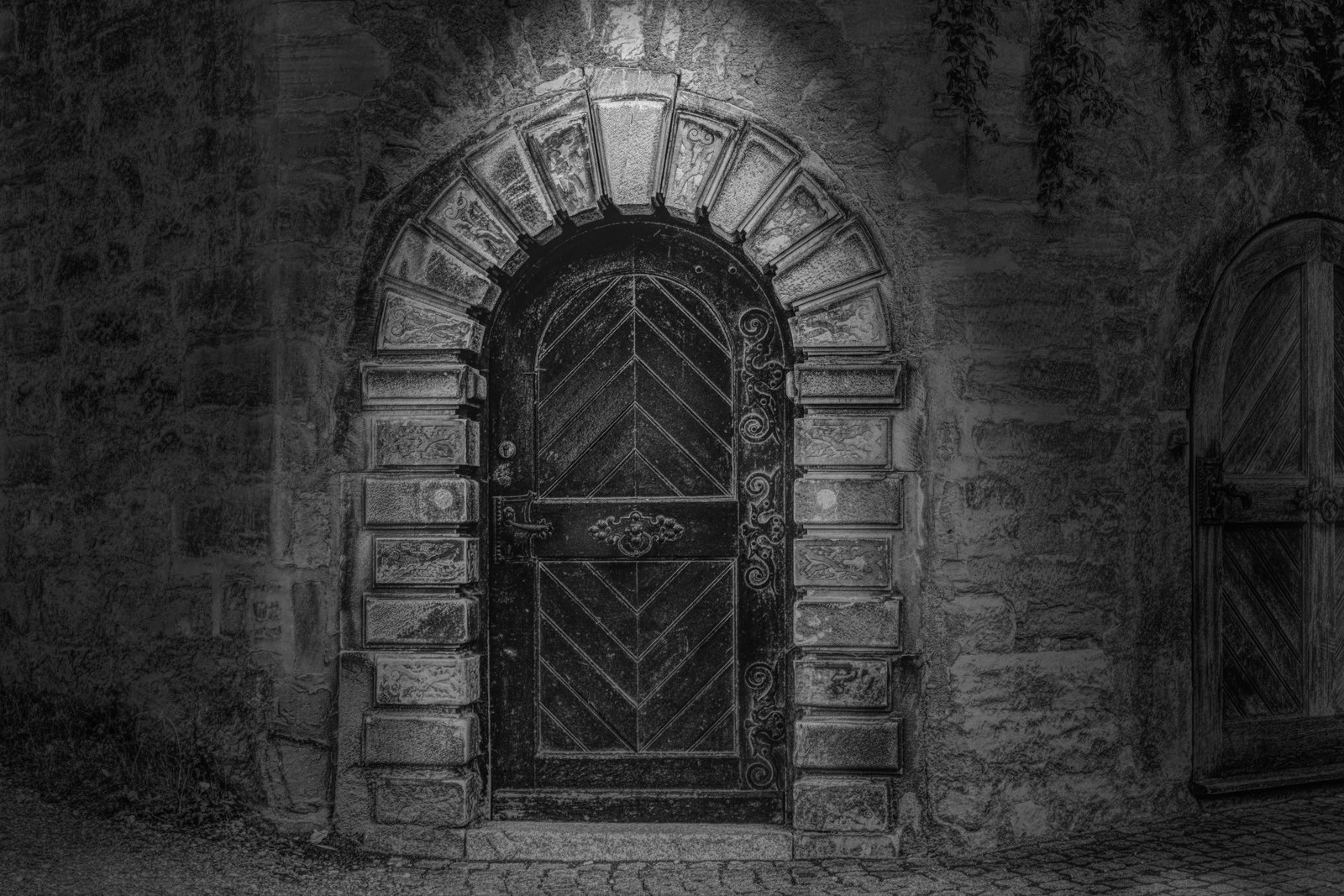 grayscale photo of arch shaped black wooden panel door goal 2k 4k 5k