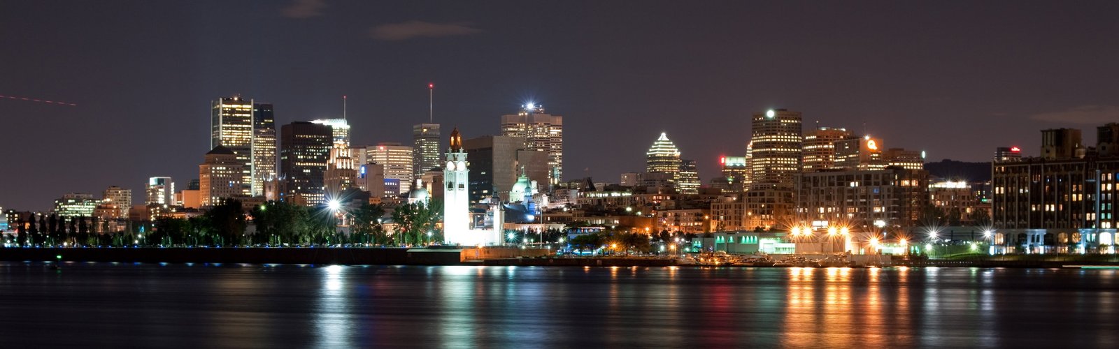 gray concrete buildings turned on lights near sea during nighttime widescreen dualmonitor dualscreen 2k 4k