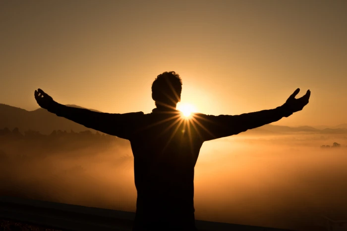 silhouette photo of man on cliff during sunset sunrise 2k