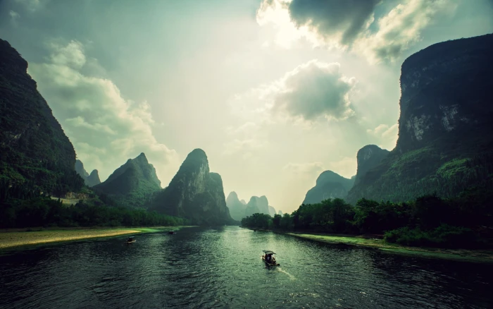 boat on body of water in middle mountains under blue and white sunny sky during daytime 2k