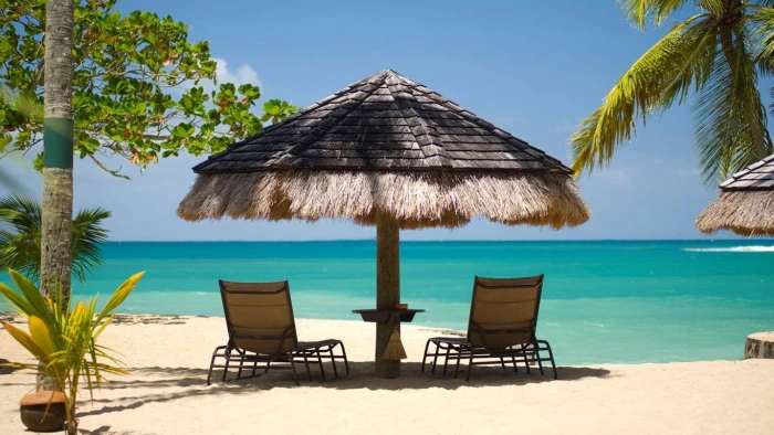 brown hut cottage island beach umbrella palm trees sand
