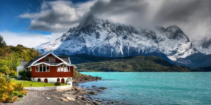 brown and white house near blue sea mountain wallpaper nature 2k