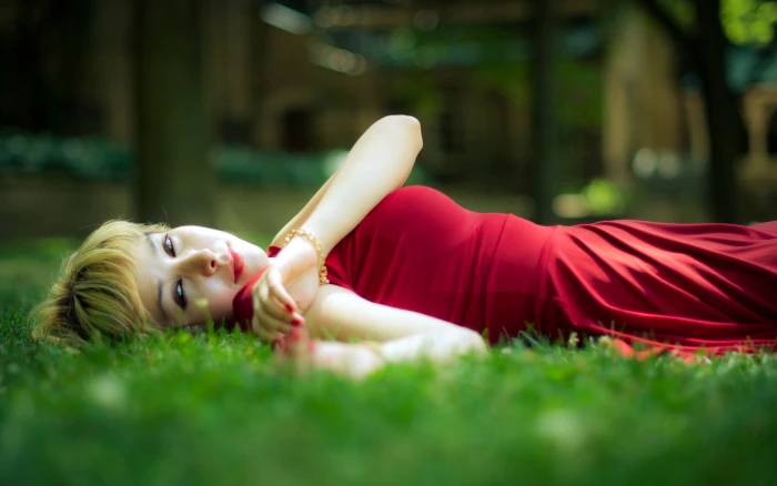 depth of field woman in red dress lying on green grass girl 2k
