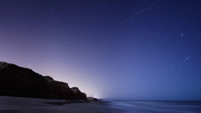 stars sea rock falls shooting star starry night sky 2k 4k