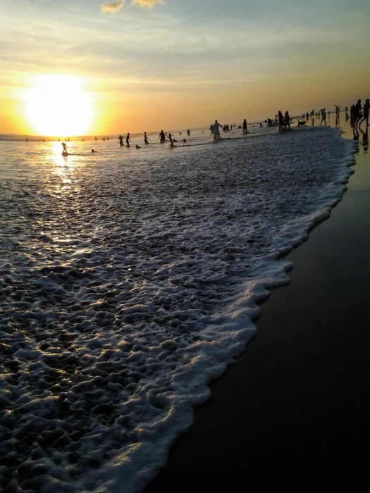 gray sand beach sunset Bali waves people sky water sea