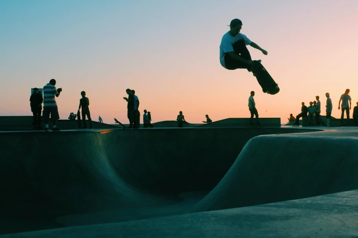 man doing trick at skateboard park during sunset several people playing on skate 2k 4k