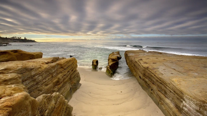 brown rock formation near body of water under white skies nature 2k