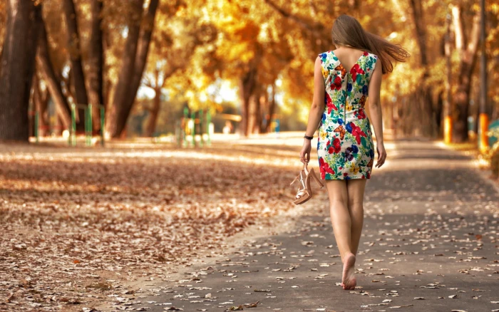 women's red white and green sleeveless dress woman wearing floral walking in gray pavement road between brown trees 2k