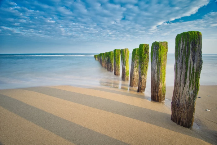 brown wooden pilars beach France atlantic ocean blue sky 2k
