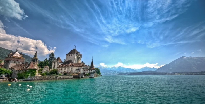 white concrete building beside body of water lake mountains 2k