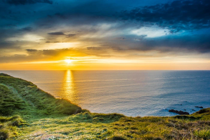 green grass beside the beach during sunrise bude united kingdom 2k