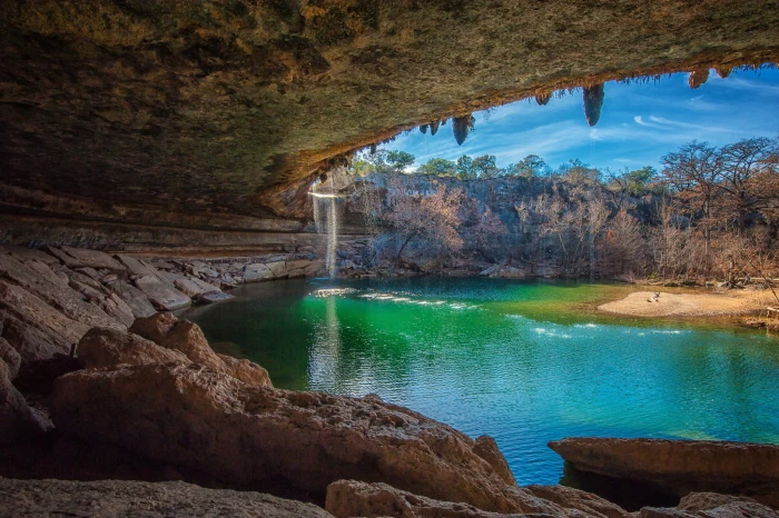 body of water near tree nature landscape cave waterfall lake 2k