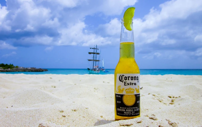 Corona Extra bottle on white sand near blue beach during daytime 2k 4k
