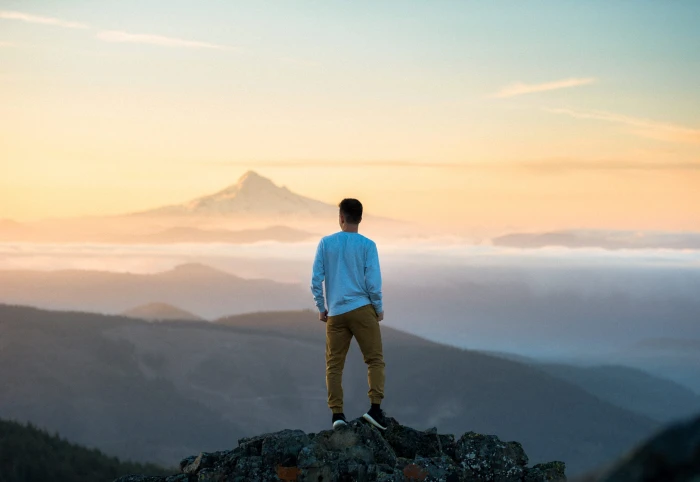 man standing on top of mountain in blue long sleeved shirt during daytime 2k 4k