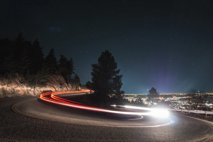 timelapse photography on curved road beside tree time lapse of vehicle lights 2k